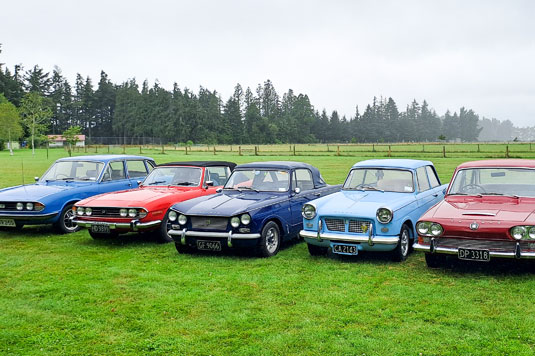 line up of triumph cars in a field